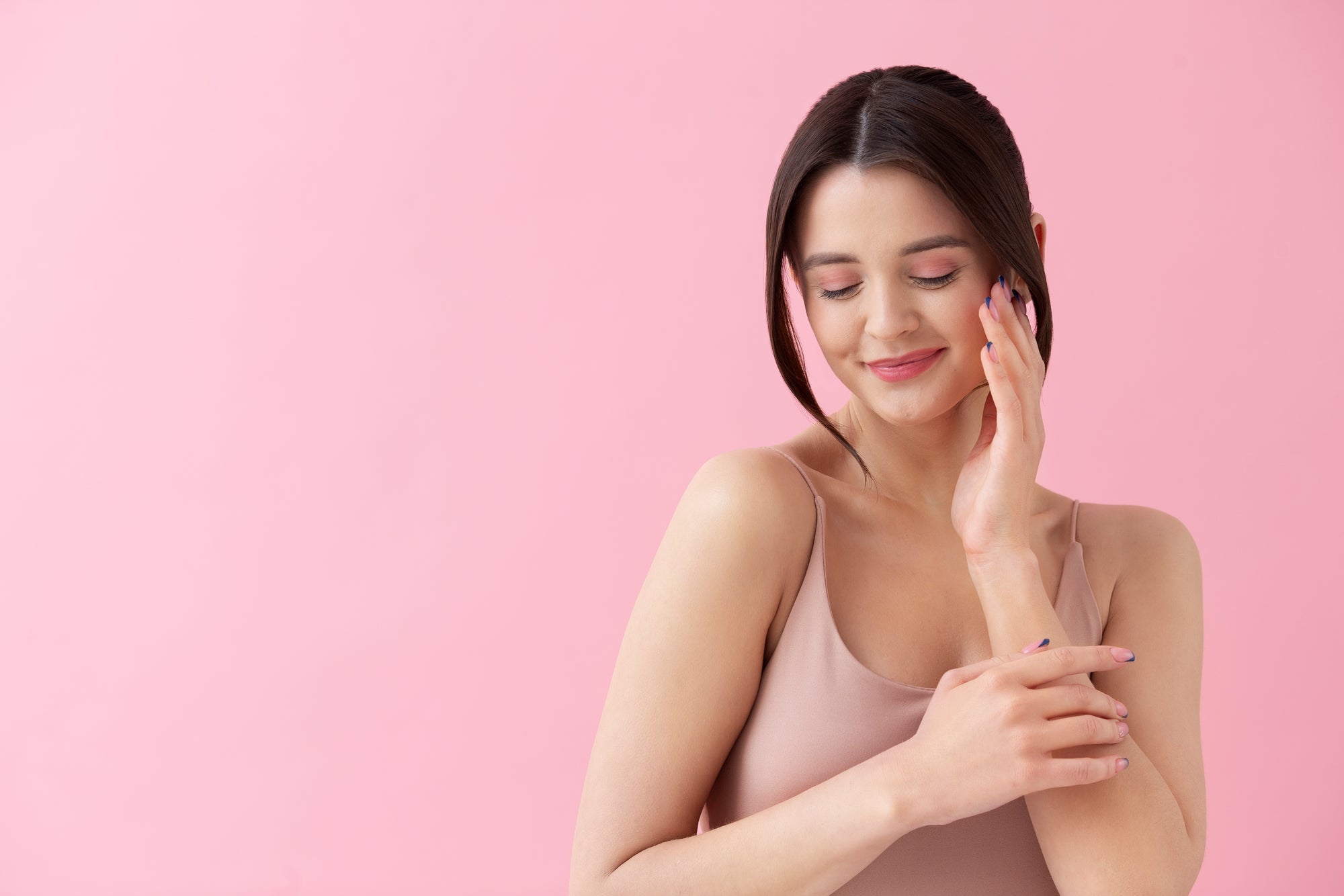 Woman touching her face against a pink background